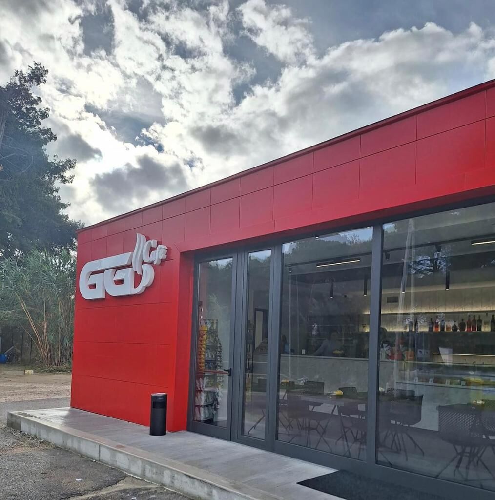 Een rood gebouw met een glazen etalage en een logo op de zijkant.
