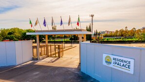 A gated entrance to a residential area with flags and a sign reading "Residence Palace". - Residence al Palace (Vasto)
