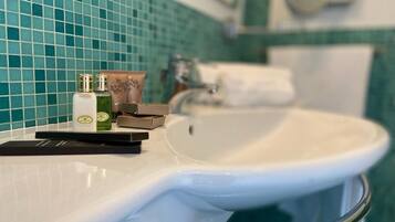 A bathroom with a white sink, a mirror, and a green tiled wall.