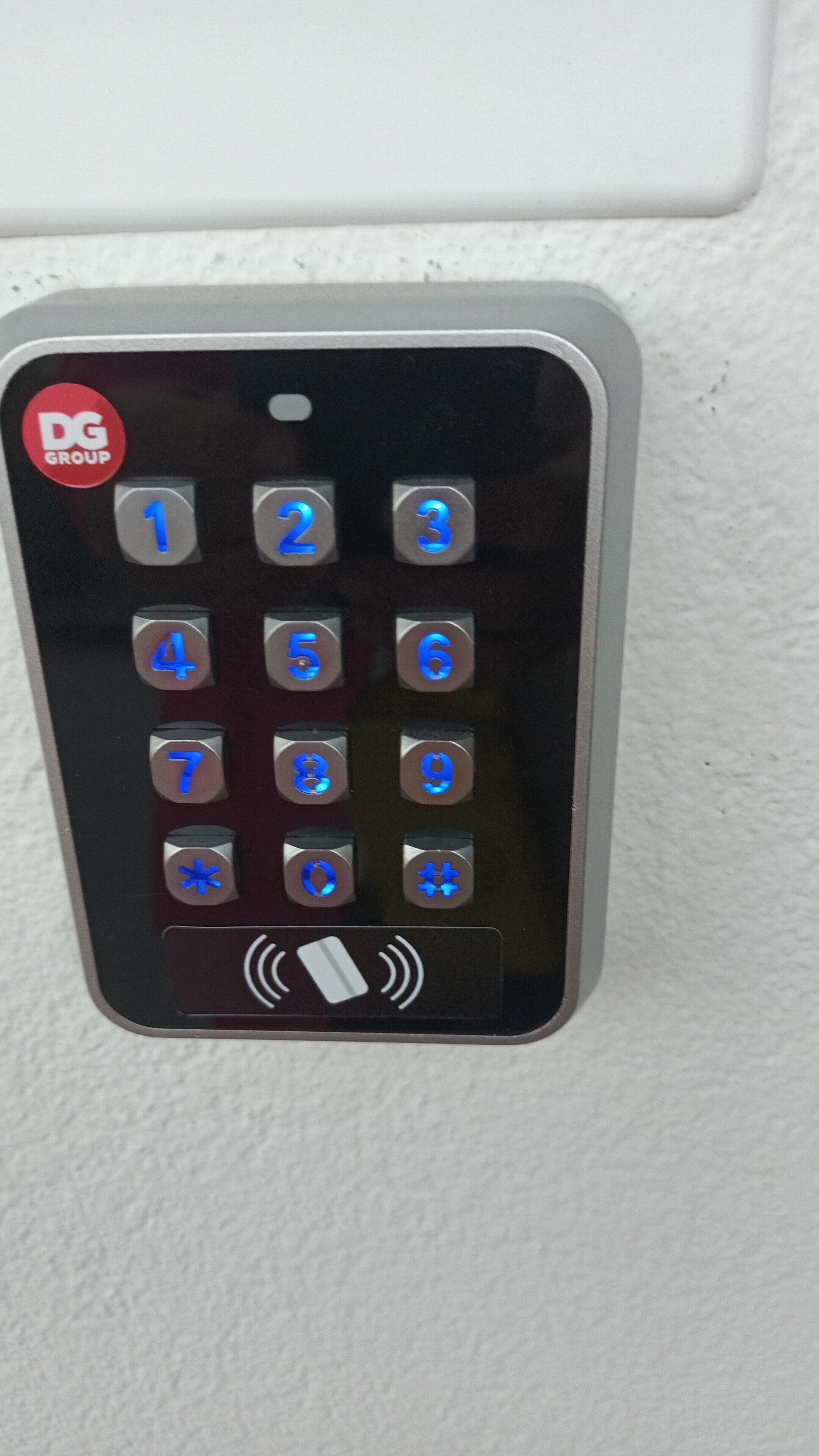 A digital keypad with numbered buttons and a DG Group logo.