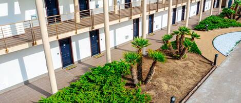 Un hotel de varios pisos con un patio central que cuenta con palmeras y un camino de ladrillo.