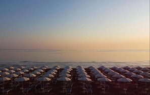 A beach with rows of umbrellas and lounge chairs. - Residence al Palace (Vasto)