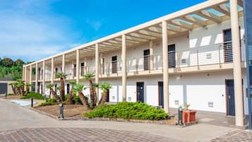 A modern building with a covered walkway, multiple balconies, and palm trees.