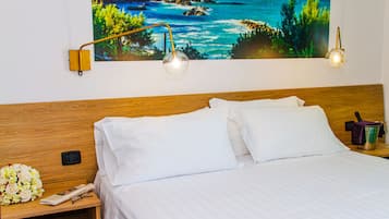 A neatly made bed with white linens, a wooden headboard, and two bedside lamps.
