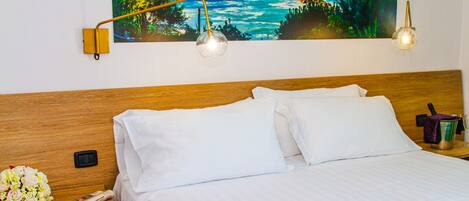 A neatly made bed with white linens, a wooden headboard, and two bedside lamps.