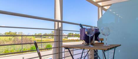 A balcony with a table, two wine glasses, and a chair.