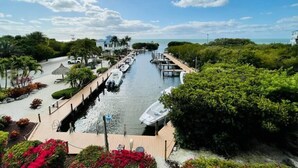 A canal with boats docked, surrounded by lush greenery and a clear sky. - Ocean View Overlooking Marina Ocean Pointe 5305 (Tavernier)