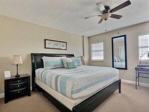 A bedroom with a bed, a nightstand, a lamp, a ceiling fan, a window with blinds, and a mirror. - Ocean View Overlooking Marina Ocean Pointe 5305 (Tavernier)