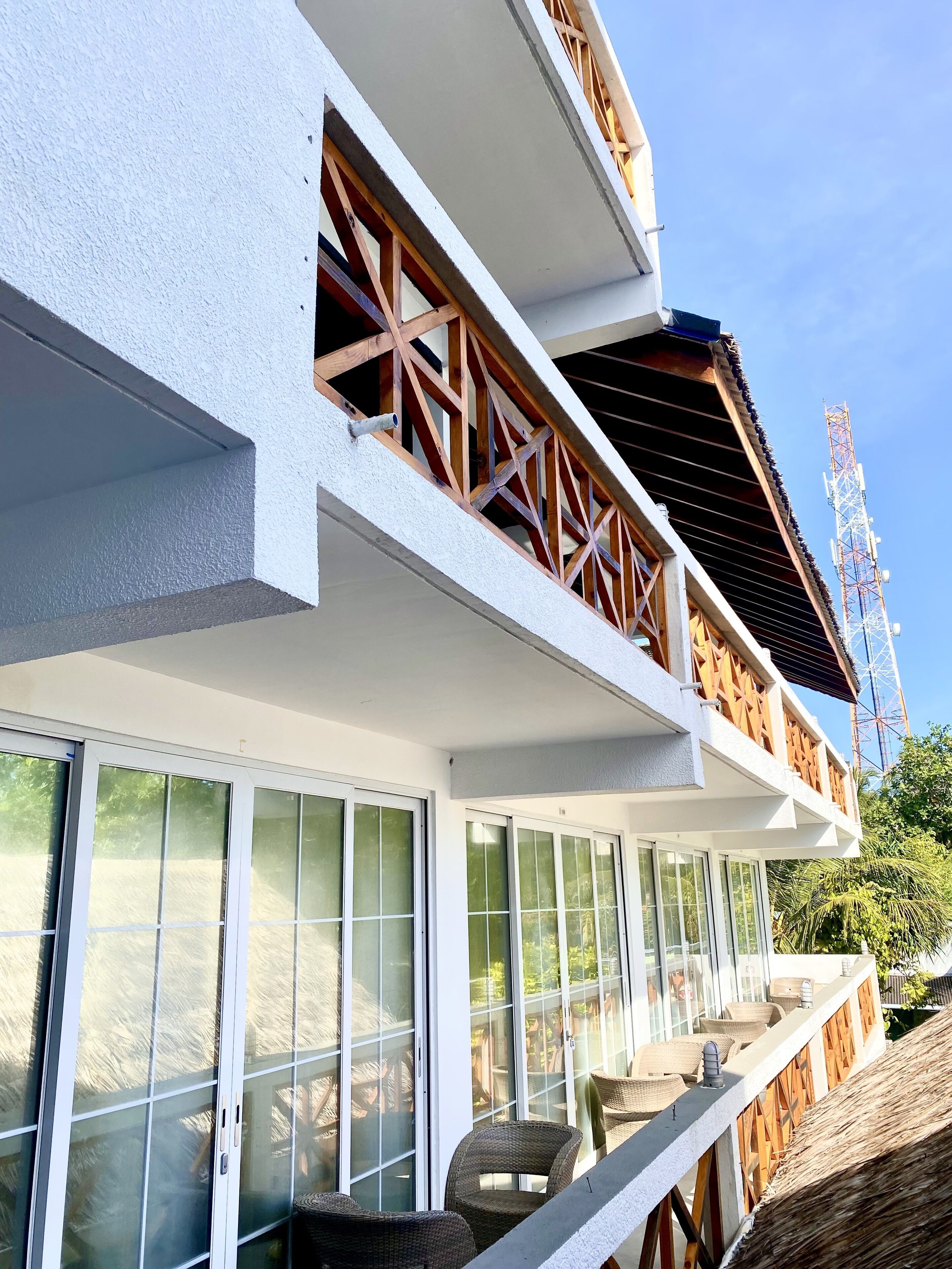 Um edifício moderno com varanda, grandes portas de vidro e mobiliário de vime.