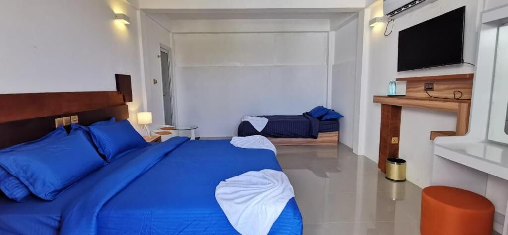 A hotel room with two beds, a TV, a small table, and a trash bin.