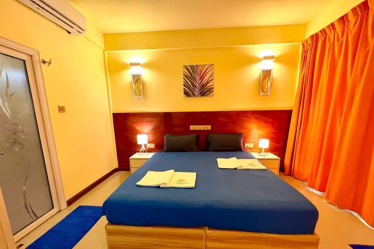 A hotel room with a large bed, two bedside tables with lamps, a wall-mounted artwork, and a sliding door.