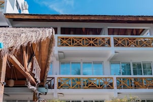 A two-story building with a balcony featuring wooden lattice railings.