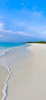 Una playa con agua azul cristalina y una orilla arenosa.