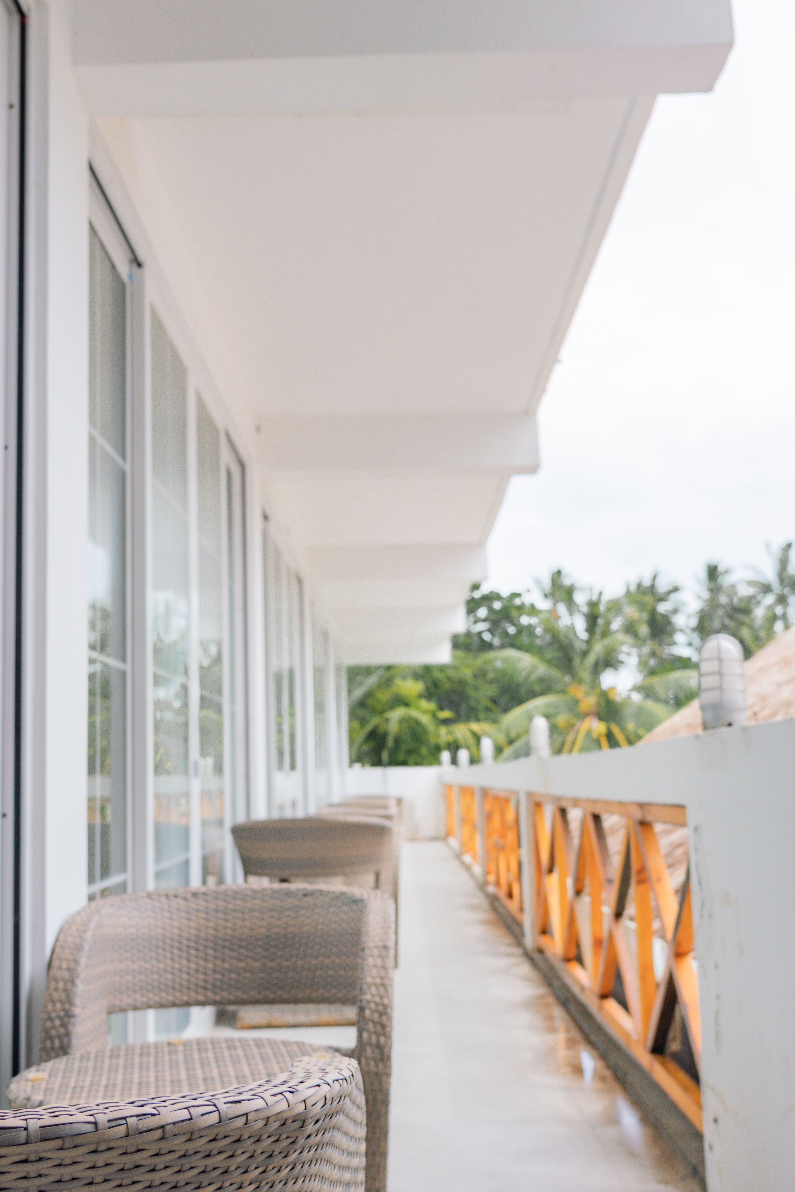 A balcony with wicker furniture and a view of palm trees.