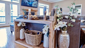 Un salon doté d’une cheminée, d’un téléviseur fixé au mur et d’objets décoratifs, notamment des vases et un panier.