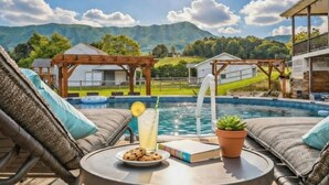 Un espace aménagé au bord de la piscine, avec des chaises longues, une table où sont disposés des biscuits et une boisson, et une vue sur les montagnes.