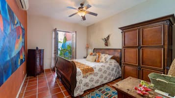 A bedroom with a bed, a dresser, a ceiling fan, and a view of the outdoors.