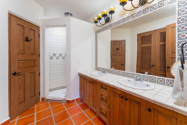 Une salle de bain avec deux lavabos, des meubles en bois, un grand miroir et un espace douche.