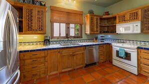 A kitchen with wooden cabinets, a refrigerator, a microwave, and a coffee maker. - Casa Patricia by Casago (Loreto)