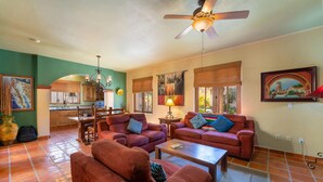 A spacious living room with two red sofas, a coffee table, and a dining area with a kitchen in the background. - Casa Patricia by Casago (Loreto)