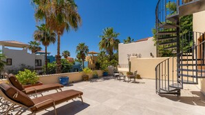 A rooftop terrace with sun loungers, palm trees, and a spiral staircase. - Casa Patricia by Casago (Loreto)
