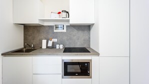 A modern kitchen with a built-in microwave, a sink, and a countertop with a kettle and a coffee maker. - Italianway - The B Village Business - 10 (Milan)