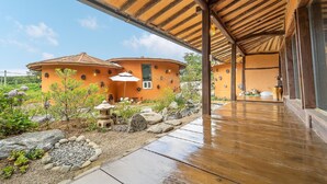 Una casa tradicional japonesa amb un balcó de fusta i un jardí amb roques i plantes.