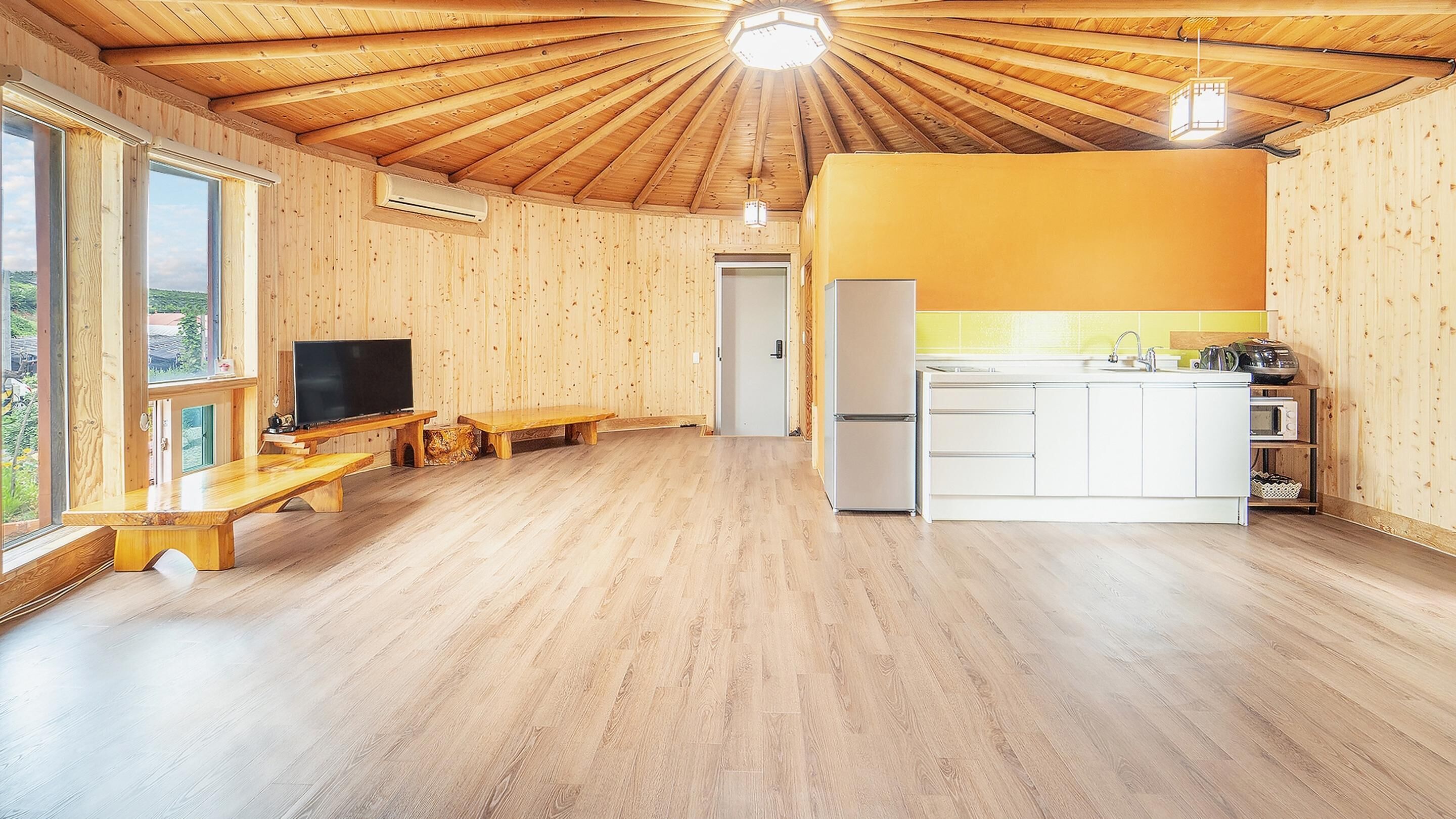 Interior de madera con cocina, comedor y televisor.