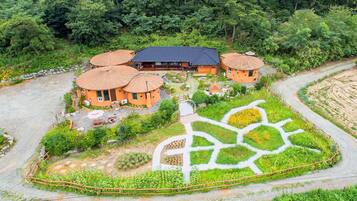 A cluster of orange-roofed buildings with a central structure, surrounded by lush greenery and a winding path.