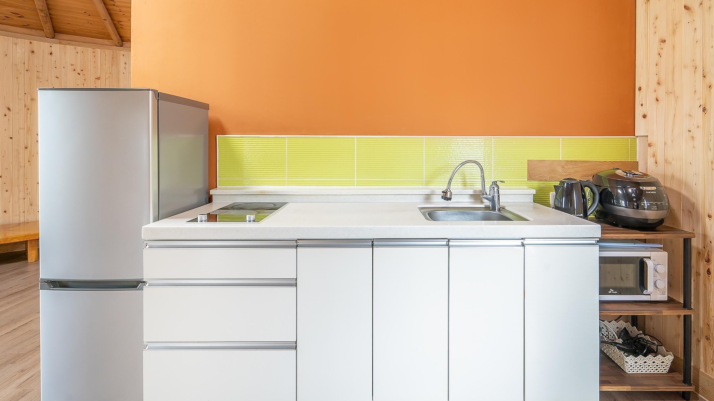 A compact kitchen with a refrigerator, sink, and a microwave.