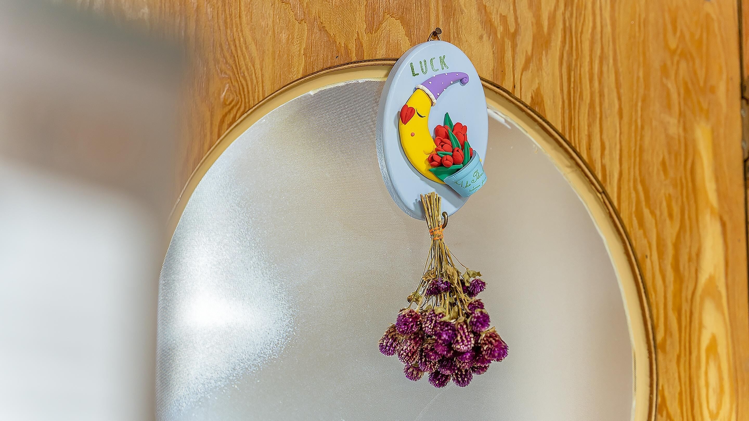 A decorative charm with a yellow background, a purple hat, and the word "LUCK" on a circular badge.