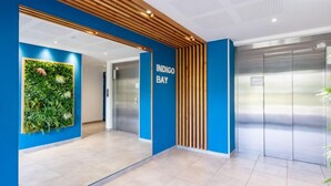Un espace d’ascenseur moderne avec un mur bleu et une enseigne indiquant « INDIGO BAY ».