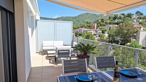 Un balcon avec une table dressée pour deux personnes, une chaise et un pot de fleurs.
