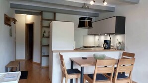 A compact kitchen with a dining area, wooden furniture, and a modern pendant light. - Fewo "zieglerei", Oberstaufen/steibis (Oberstaufen)