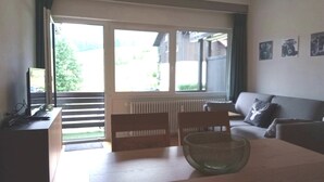 A living room with a sofa, a table with a glass bowl, a TV, and a window with blinds. - Fewo "zieglerei", Oberstaufen/steibis (Oberstaufen)