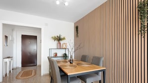 A dining area with a wooden table, grey chairs, and a vertical wooden panel wall. - Casa Angel Malaga (Málaga)