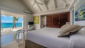 Una camera da letto con un letto grande, vista sull'oceano, una ventola a soffitto e un armadio in legno.