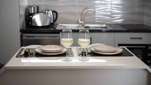 Cozinha moderna com painel de aço inoxidável, pia e bancada com dois copos de vinho branco e pratos.