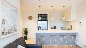 A modern kitchen with a central island, bar stools, a refrigerator, and pendant lighting. - Aqua Views of the bay in Mornington (Mornington)