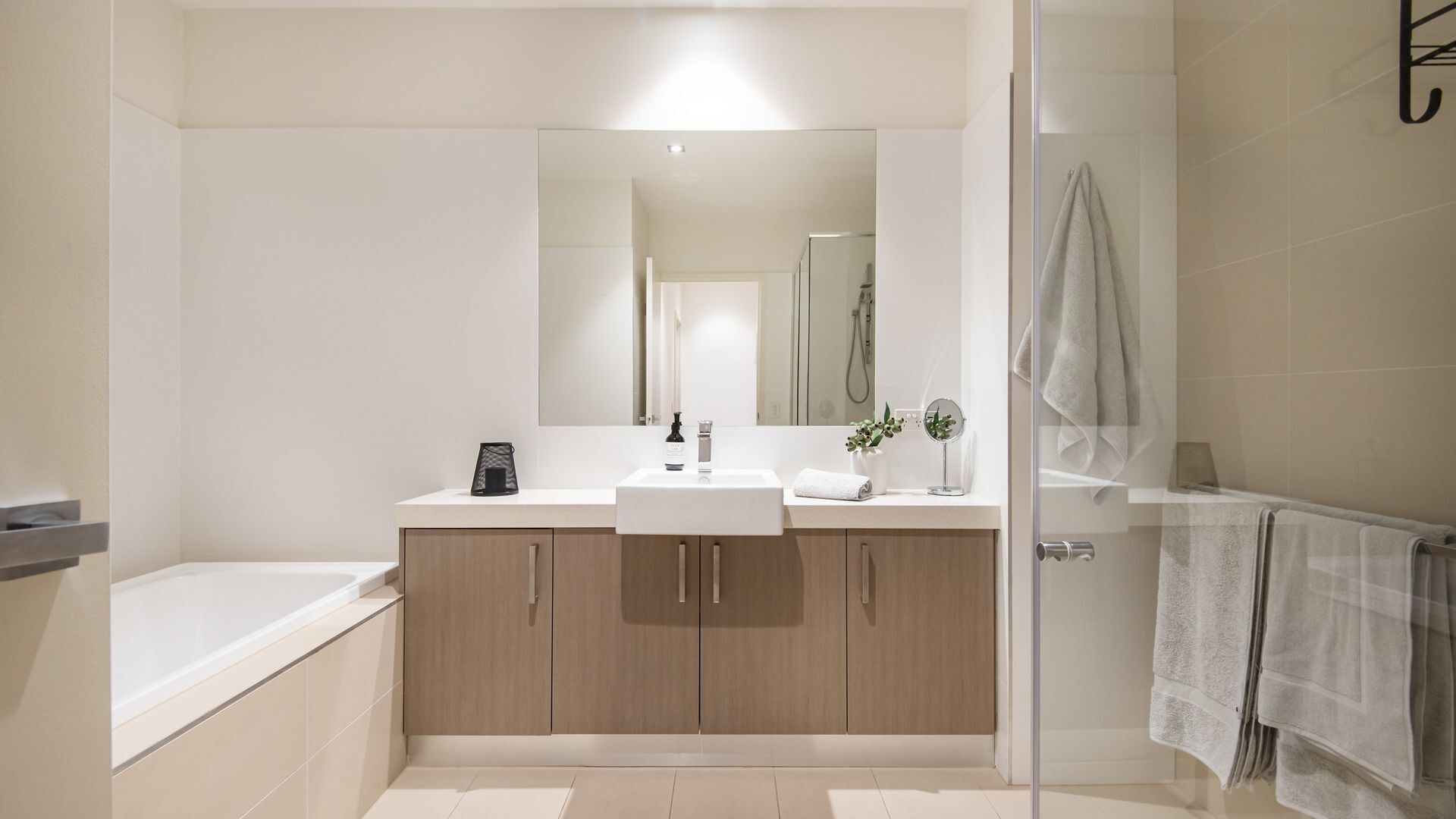 A modern bathroom with a large mirror, a sink, and a shower area.
