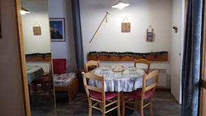Un comedor con una mesa y sillas de madera, una lámpara colgante y una guirnalda navideña en la pared.