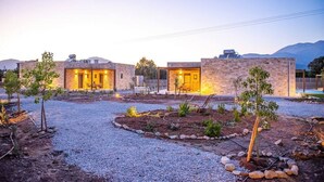 Un edificio moderno con varias habitaciones, un camino de grava y pequeños árboles.