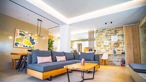 Una sala de estar moderna con un sofá modular, una mesa de centro de madera y una cocina al fondo.