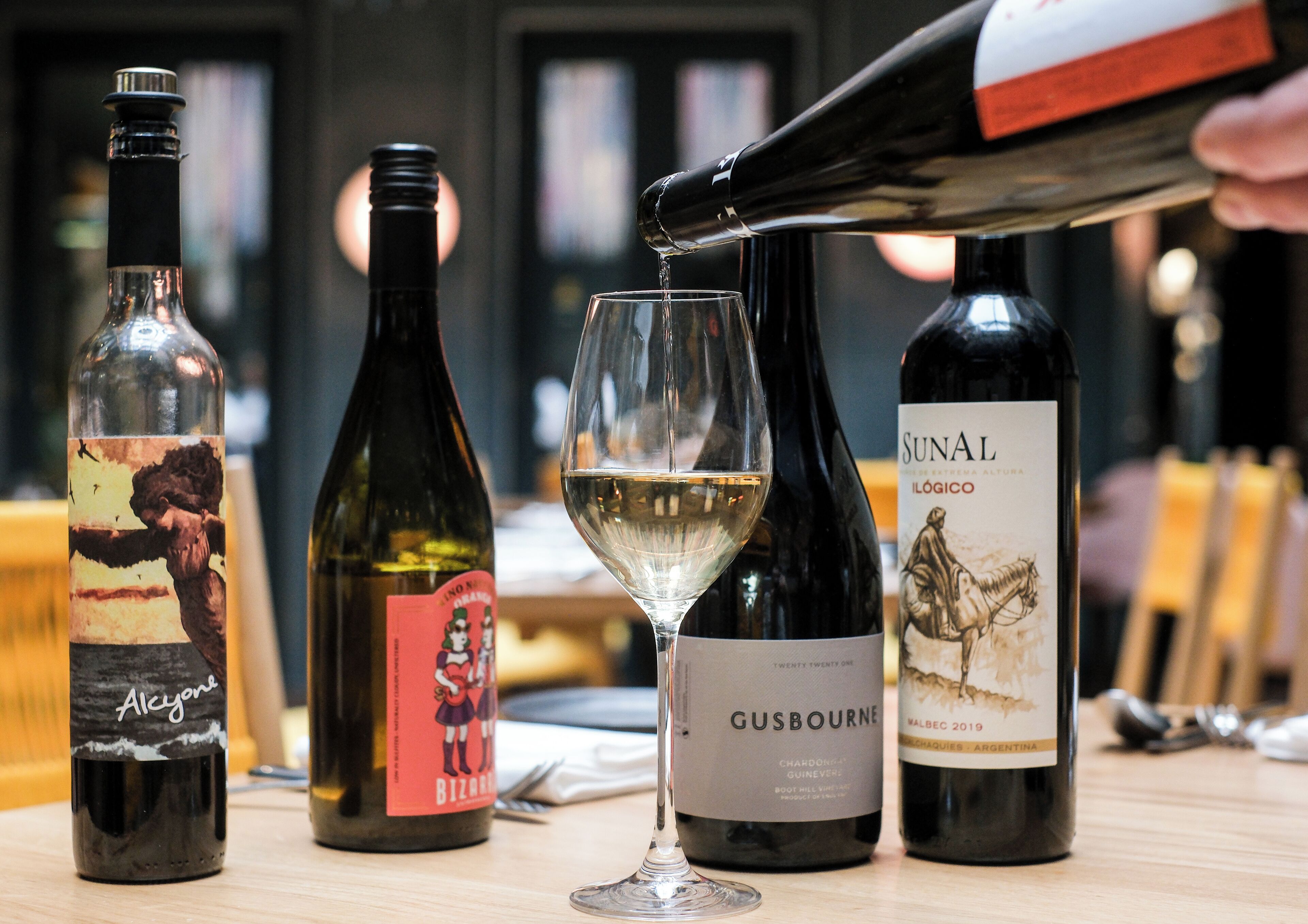 Una mesa con tres botellas de vino y una copa.