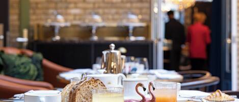 A breakfast setting with croissants, orange juice, and a flamingo-shaped glass.