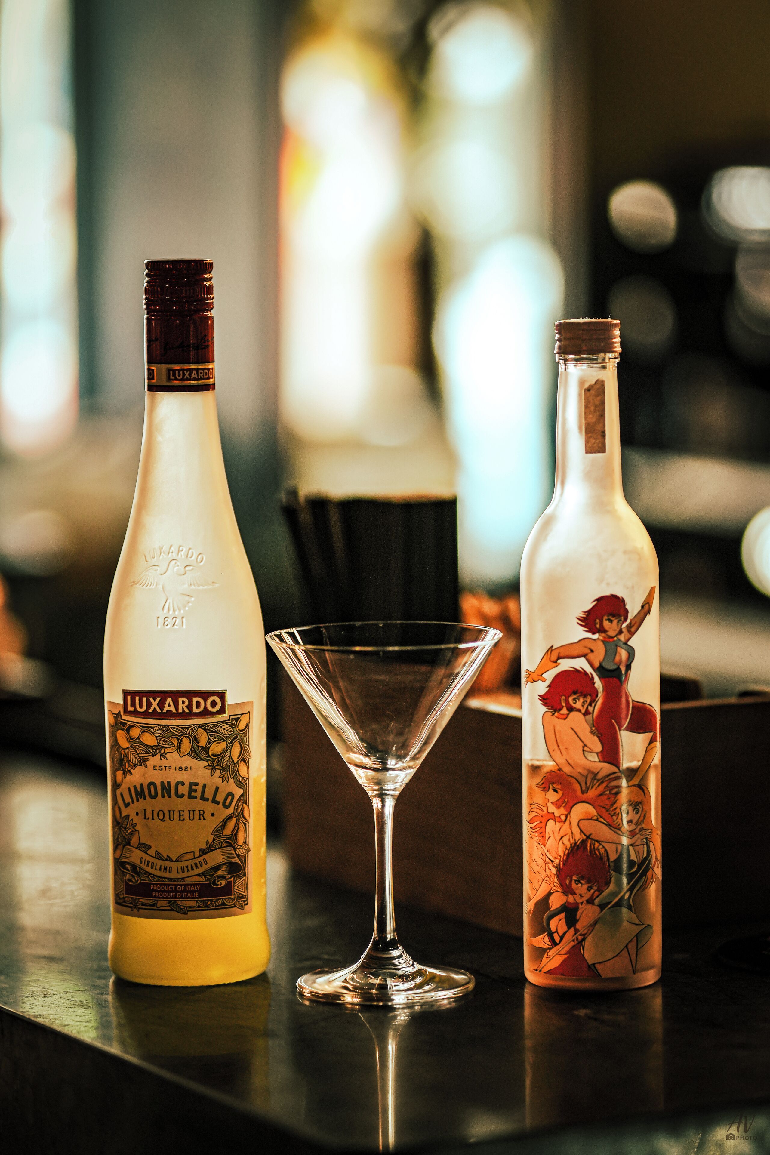 Two bottles of Luxardo Limoncello and a martini glass on a bar counter.