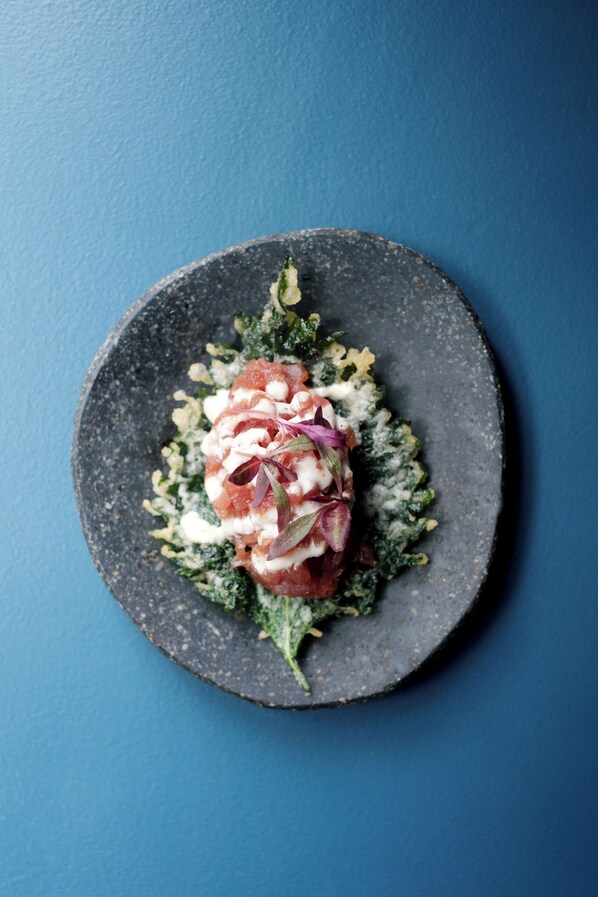 A dark plate with a salad on a blue background. - Sun Street Hotel Shoreditch (London)