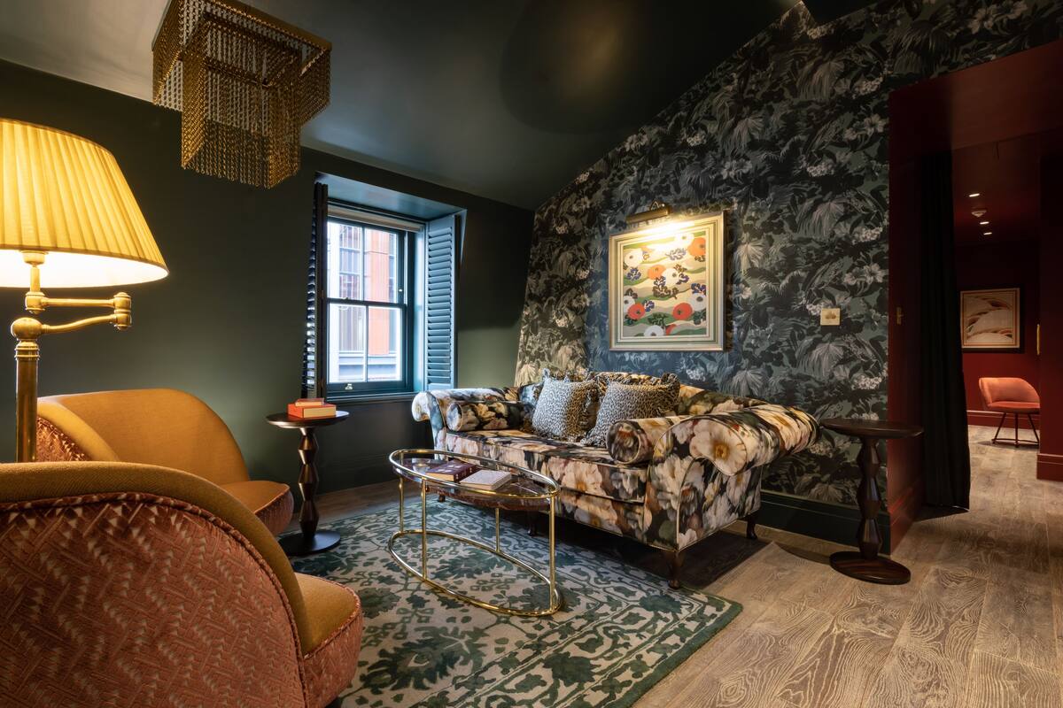 A cozy living room with a floral-patterned sofa, a round coffee table, and a lamp.
