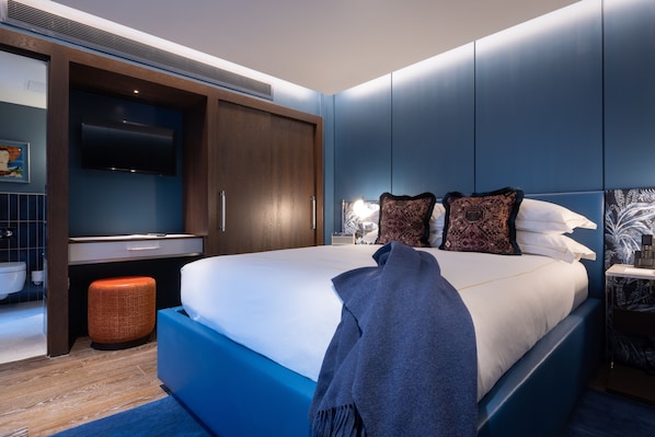 A modern bedroom with a large bed, built-in wardrobe, and a bedside table with a lamp. - Sun Street Hotel Shoreditch (London)