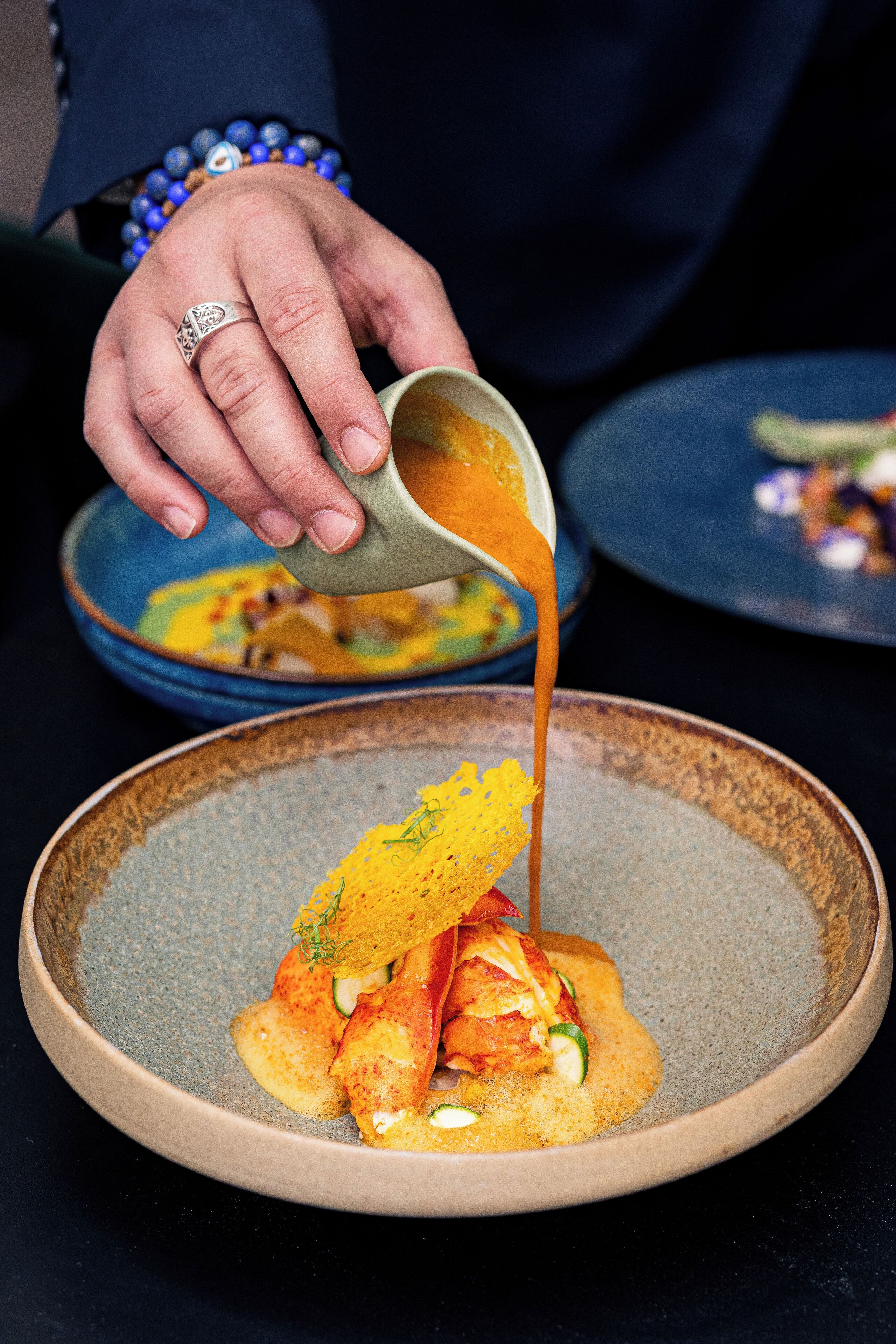 A person pouring sauce over a dish.
